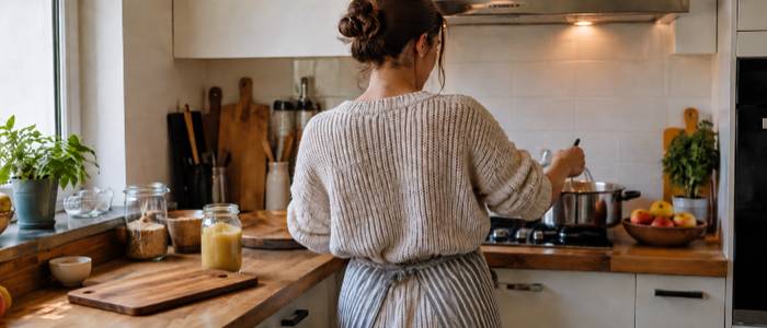 Woman cooking a homemade applesauce recipe on the stove in a cozy kitchen.